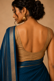 Woman wearing a blue saree with a beige blouse against a beige background