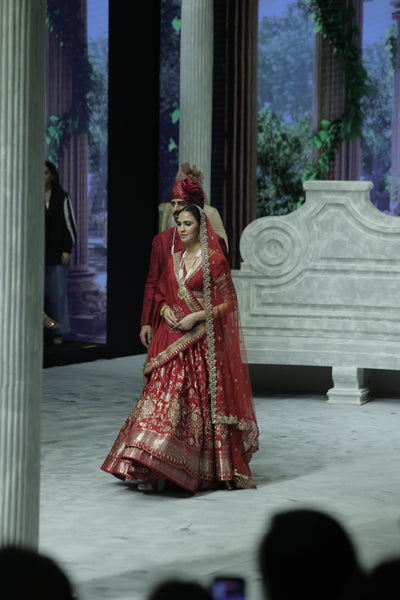 RED BROCADE DOUBLE LAYER LEHENGA PAIRED WITH A RED DUPION EMBROIDERED BLOUSE, RED EMBROIDERED DUPATTA, AND RED EMBROIDERED NET VEIL. (4 PCS)