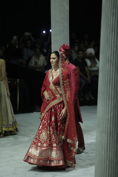 RED BROCADE DOUBLE LAYER LEHENGA PAIRED WITH A RED DUPION EMBROIDERED BLOUSE, RED EMBROIDERED DUPATTA, AND RED EMBROIDERED NET VEIL. (4 PCS)
