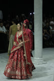RED BROCADE DOUBLE LAYER LEHENGA PAIRED WITH A RED DUPION EMBROIDERED BLOUSE, RED EMBROIDERED DUPATTA, AND RED EMBROIDERED NET VEIL. (4 PCS)