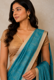 Woman wearing a blue saree with a beige blouse against a neutral background
