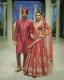 RED BROCADE DOUBLE LAYER LEHENGA PAIRED WITH A RED DUPION EMBROIDERED BLOUSE, RED EMBROIDERED DUPATTA, AND RED EMBROIDERED NET VEIL. (4 PCS)
