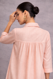 A SOFT PEACH TUNIC SHAPED IN FLUID SIMPLICITY, BALANCING STRUCTURE AND UNDERSTATED ELEGANCE