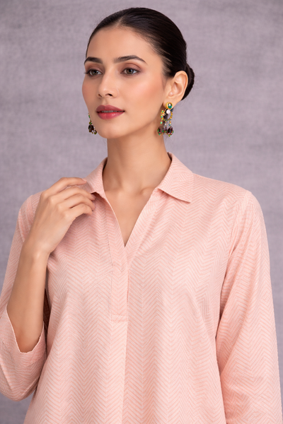 A SOFT PEACH TUNIC SHAPED IN FLUID SIMPLICITY, BALANCING STRUCTURE AND UNDERSTATED ELEGANCE