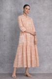 A SOFT PEACH DRESS WITH A FLUID, TIERED SILHOUETTE AND UNDERSTATED GRACE
