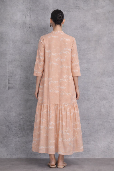A SOFT PEACH DRESS WITH A FLUID, TIERED SILHOUETTE AND UNDERSTATED GRACE