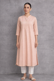 A SOFT PEACH TUNIC MARKED BY CLEAN LINES AND GENTLE MOVEMENT