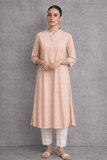 A SOFT PEACH TUNIC MARKED BY CLEAN LINES AND GENTLE MOVEMENT