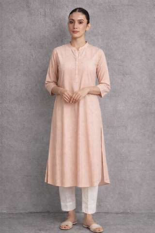 A SOFT PEACH TUNIC MARKED BY CLEAN LINES AND GENTLE MOVEMENT