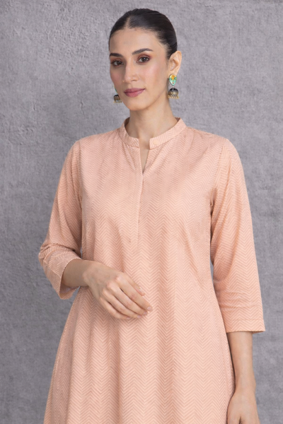 A SOFT PEACH TUNIC MARKED BY CLEAN LINES AND GENTLE MOVEMENT