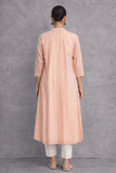 A SOFT PEACH TUNIC MARKED BY CLEAN LINES AND GENTLE MOVEMENT