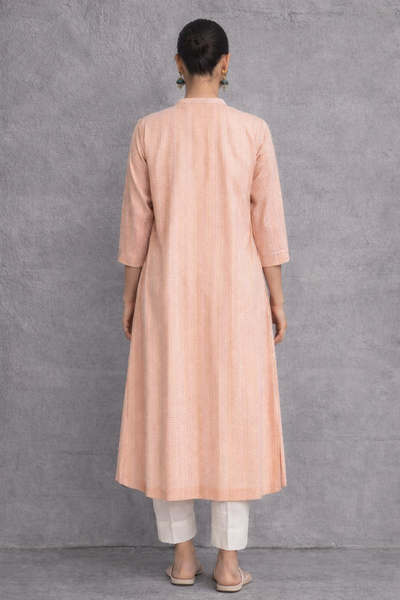 A SOFT PEACH TUNIC MARKED BY CLEAN LINES AND GENTLE MOVEMENT