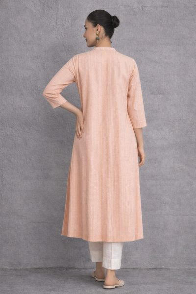 A SOFT PEACH TUNIC MARKED BY CLEAN LINES AND GENTLE MOVEMENT