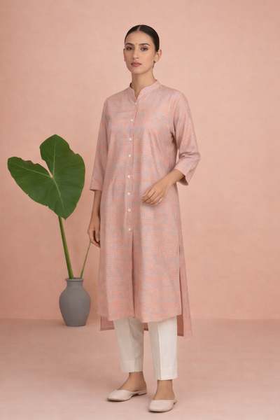 A PEACH TUNIC SHAPED IN FLUID EASE AND UNDERSTATED REFINEMENT