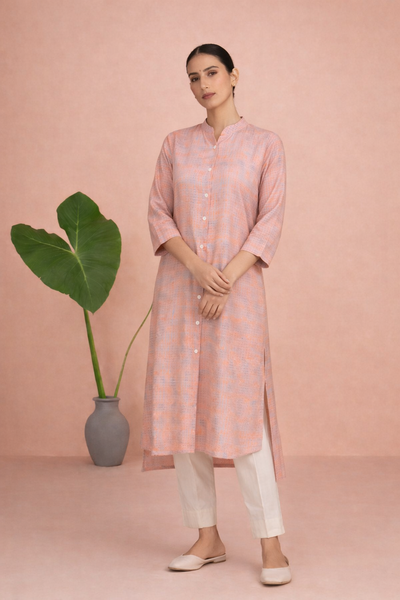 A PEACH TUNIC SHAPED IN FLUID EASE AND UNDERSTATED REFINEMENT