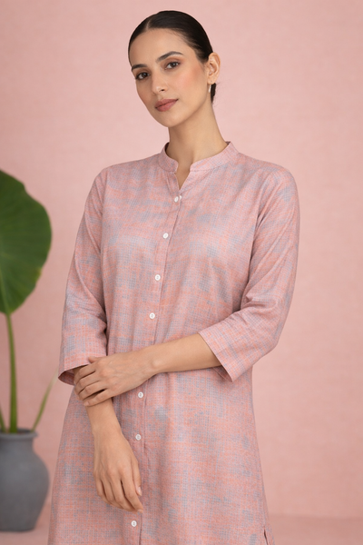 A PEACH TUNIC SHAPED IN FLUID EASE AND UNDERSTATED REFINEMENT