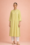 A SOFT GREEN TUNIC SHAPED IN FLUID SIMPLICITY BALANCING EASE AND UNDERSTATED ELEGANCE
