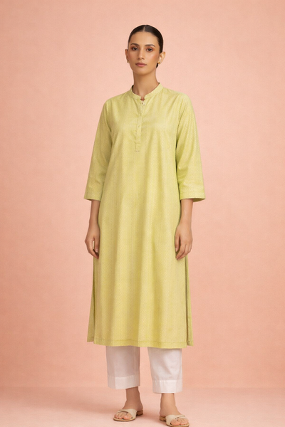 A SOFT GREEN TUNIC SHAPED IN FLUID SIMPLICITY BALANCING EASE AND UNDERSTATED ELEGANCE