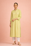 A SOFT GREEN TUNIC SHAPED IN FLUID SIMPLICITY BALANCING EASE AND UNDERSTATED ELEGANCE