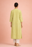 A SOFT GREEN TUNIC SHAPED IN FLUID SIMPLICITY BALANCING EASE AND UNDERSTATED ELEGANCE