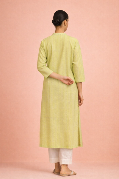 A SOFT GREEN TUNIC SHAPED IN FLUID SIMPLICITY BALANCING EASE AND UNDERSTATED ELEGANCE