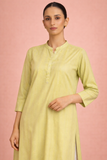 A SOFT GREEN TUNIC SHAPED IN FLUID SIMPLICITY BALANCING EASE AND UNDERSTATED ELEGANCE