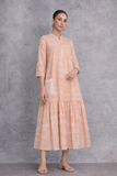 A SOFT PEACH DRESS WITH A FLUID, TIERED SILHOUETTE AND UNDERSTATED GRACE