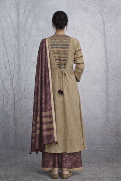 A LINEN JACKET LAYERED OVER A BROWN TUSSAR SAREE, BLENDING STRUCTURE WITH SOFT DRAPE.