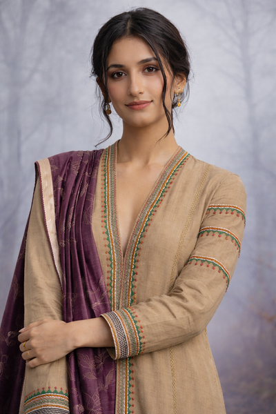 A LINEN JACKET LAYERED OVER A BROWN TUSSAR SAREE, BLENDING STRUCTURE WITH SOFT DRAPE.