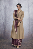 A LINEN JACKET LAYERED OVER A BROWN TUSSAR SAREE, BLENDING STRUCTURE WITH SOFT DRAPE.