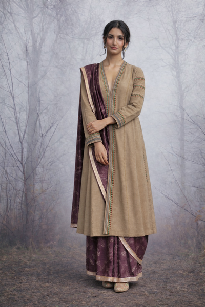 A LINEN JACKET LAYERED OVER A BROWN TUSSAR SAREE, BLENDING STRUCTURE WITH SOFT DRAPE.