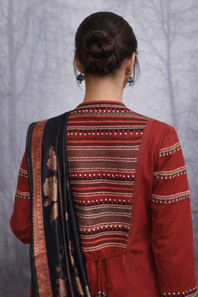 A MADDER RED LINEN JACKET PAIRED WITH A BLACK TUSSAR SILK SAREE.