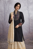 A BLACK EMBROIDERED VISCOSE DUPION JACKET PAIRED WITH A BEIGE TUSSAR SILK SAREE.