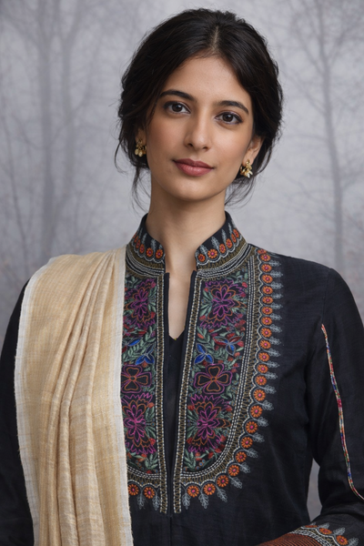 A BLACK EMBROIDERED VISCOSE DUPION JACKET PAIRED WITH A BEIGE TUSSAR SILK SAREE.