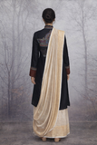 A BLACK EMBROIDERED VISCOSE DUPION JACKET PAIRED WITH A BEIGE TUSSAR SILK SAREE.