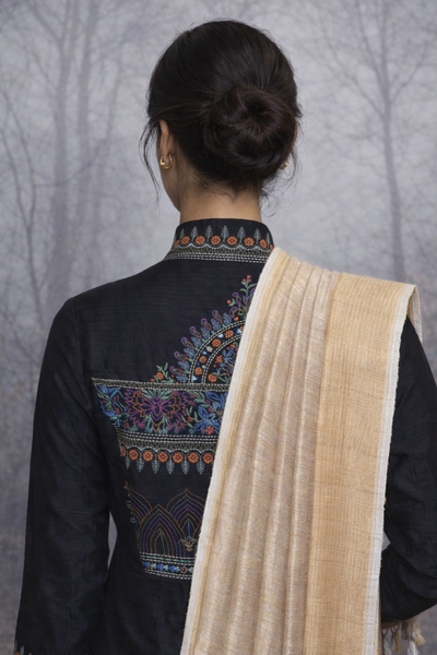 A BLACK EMBROIDERED VISCOSE DUPION JACKET PAIRED WITH A BEIGE TUSSAR SILK SAREE.