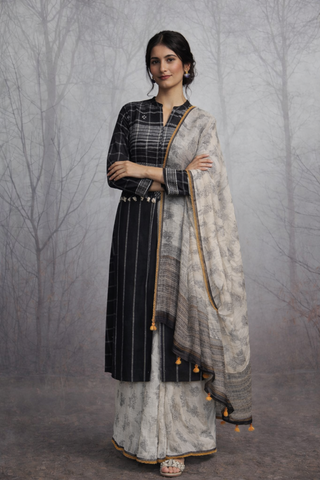 A LINEN JACKET LAYERED OVER A SOFTLY DRAPED TUSSAR SAREE.