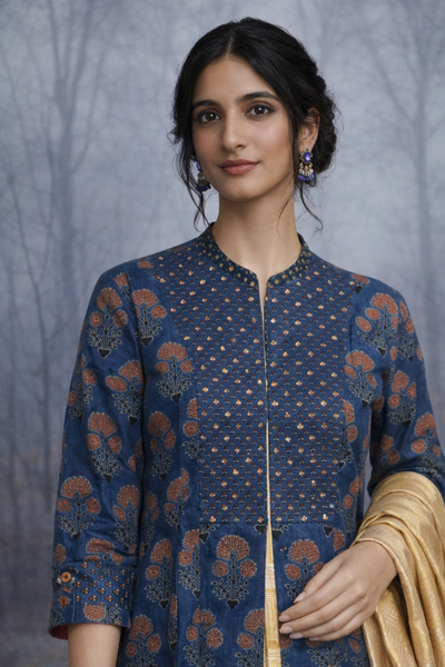 A STRUCTURED BLUE JACKET WITH A SOFT SILK TISSUE SAREE, BALANCED IN CONTRAST AND EASE.