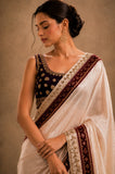 Woman wearing a traditional saree with intricate patterns on a beige background