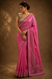 Woman wearing a pink saree with a brown background