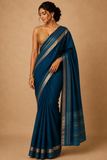 Woman wearing a blue saree with a beige background