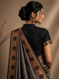 Woman wearing a black blouse with a brown saree against a beige background